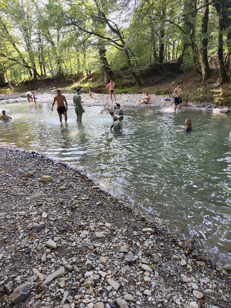 После купальни с голубой глиной люди купаются в горной реке